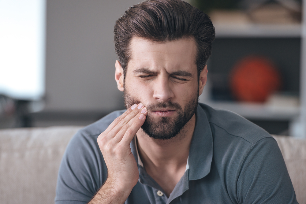 man experiencing tooth pain at home